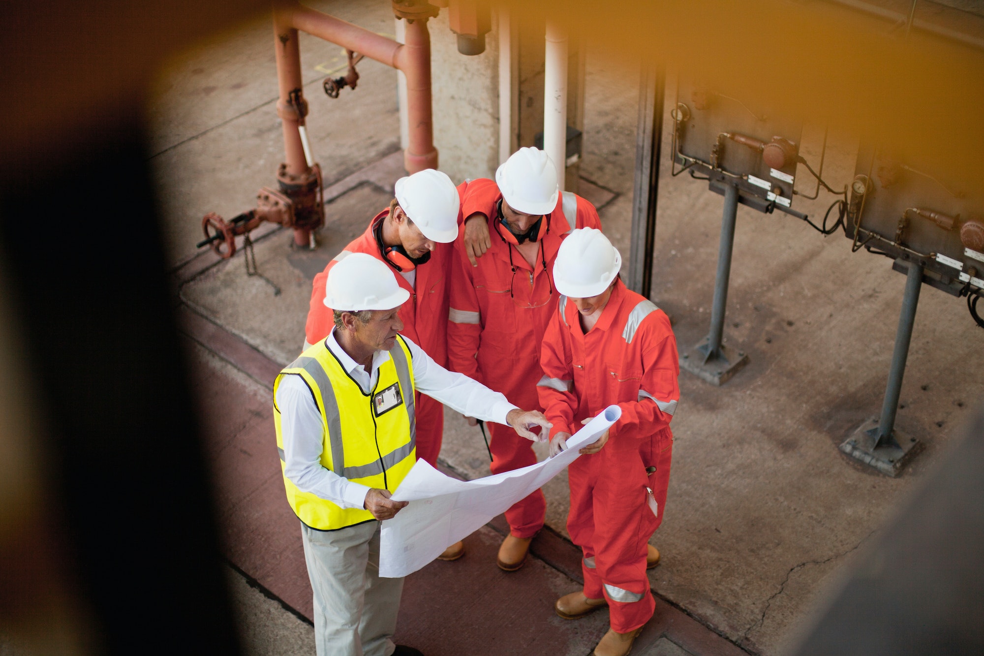 Workers with blueprints at oil refinery